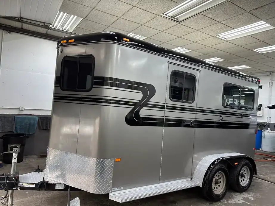 Silver two-horse trailer with black stripes in the detailing bay