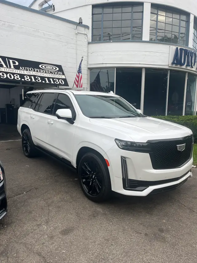 White Cadillac Escalade parked out front of the shop under the AP sign