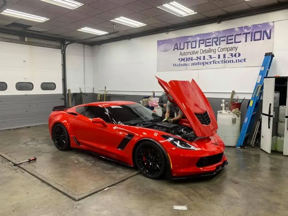 Red Corvette Z06 with the hood up inside the shop