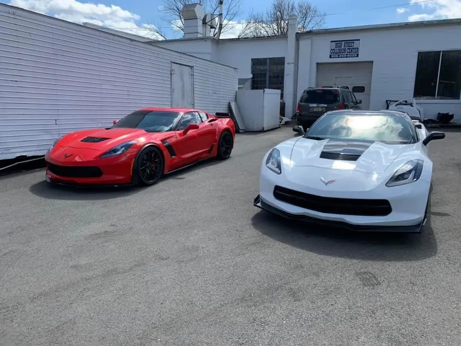 Red and white Corvettes parked outside the shop